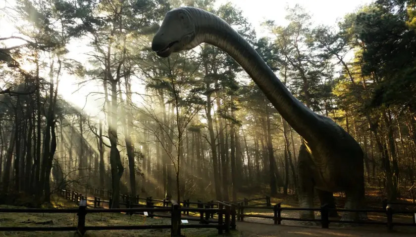 Dinozaur w lesie, jedna z atrakcji Solca Kujawskiego, w promieniach słońca.