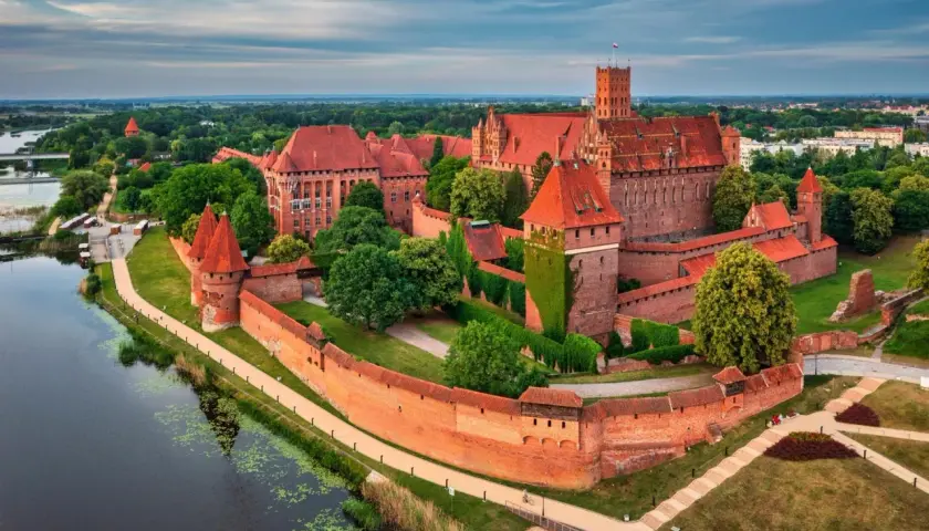 Malbork, największy zamek w Polsce, majestatycznie wznosi się nad rzeką Nogat. Potężne ceglane mury i liczne wieże świadczą o jego bogatej historii.