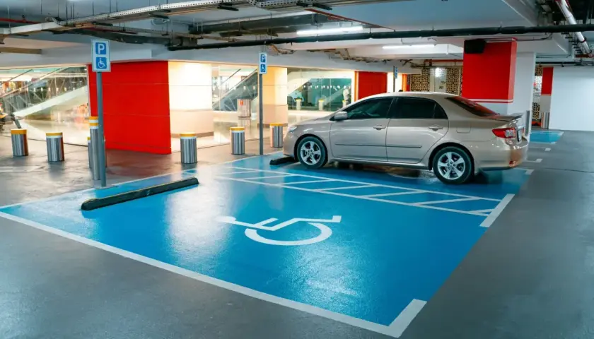 Miejsce parkingowe dla osób z niepełnosprawnościami, symbol wózka inwalidzkiego. Ułatwienia dla niepełnosprawnych przy rejestracji samochodu.