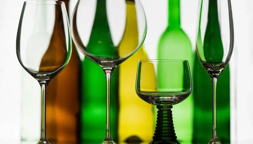Leere Weingläser stehen vor bunten Flaschen. Die richtige rotwein temperatur ist entscheidend für den Genuss.