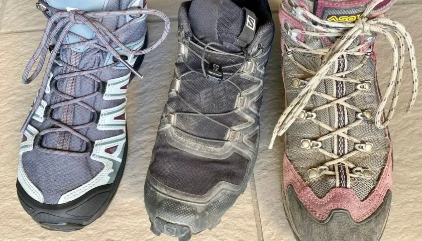 Three hiking boots: a low-cut grey boot, a mid-cut black boot, and a high-cut grey and pink boot.