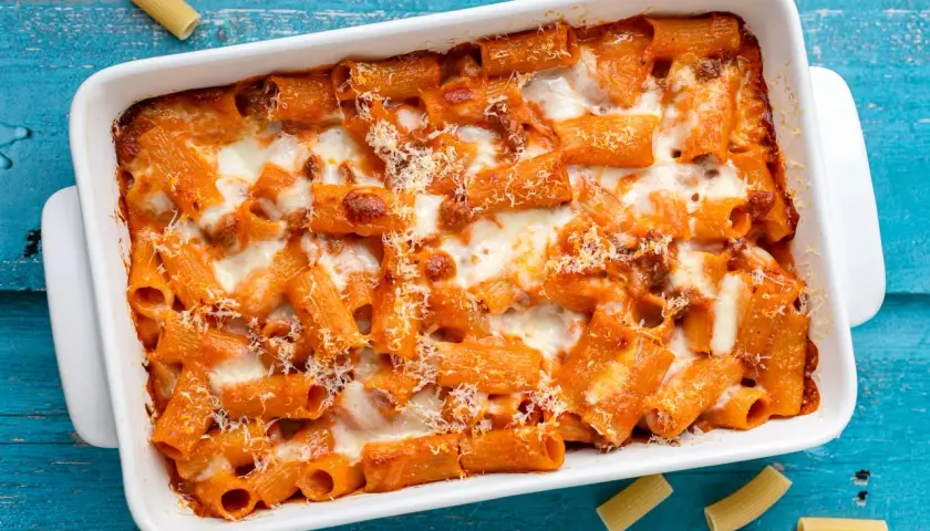 Un invitante piatto di pasta al forno, con rigatoni conditi con sugo rosso e abbondante formaggio fuso, pronto per essere gustato.
