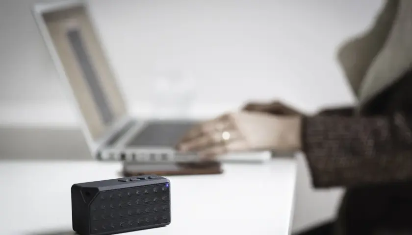 Mały głośnik z niebieską diodą obok laptopa. Dowiedz się, jak sprawdzić, czy komputer ma Bluetooth.