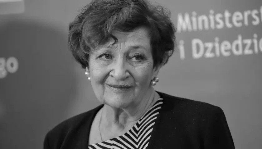 Uśmiechnięta Ewa Dałkowska, aktorka znana z wielu filmów, w eleganckiej stylizacji.