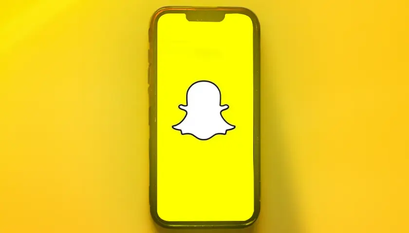 Telefon z logo Snapchata. Dowiedz się, jak odzyskać dni na Snapie, gdy przypadkowo je stracisz.