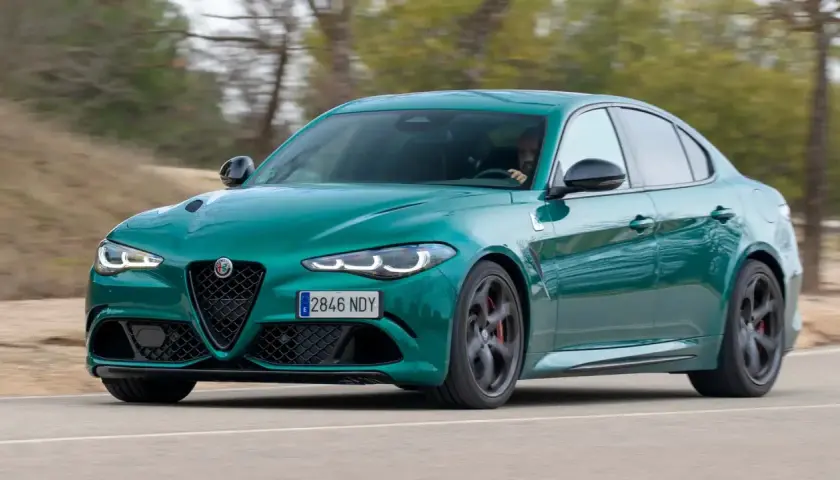 Un Alfa Romeo Giulia verde es conducido en una carretera, con el conductor visible al volante. Es una prueba del coche.