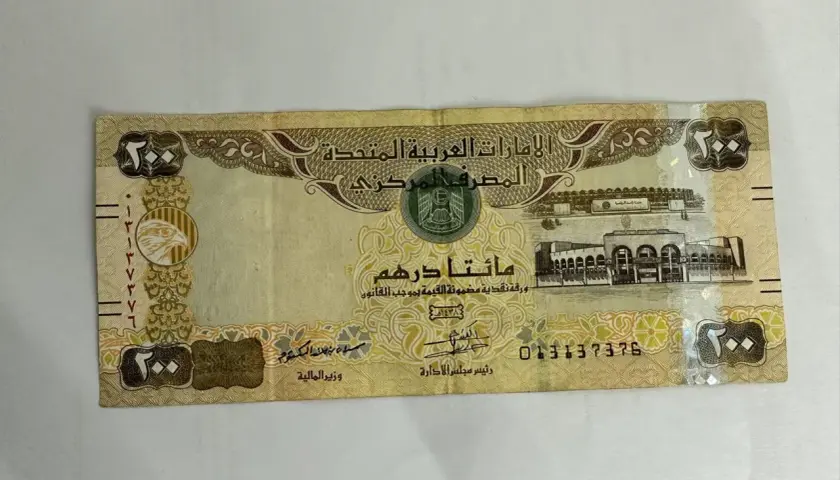 Banknot 200 dirhamów, waluta w Dubaju, z wizerunkiem sokoła i budynków.