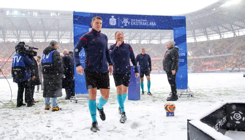 Sędziowie w śnieżny dzień wchodzą na boisko przed meczem Jagiellonia Białystok – GKS Katowice.
