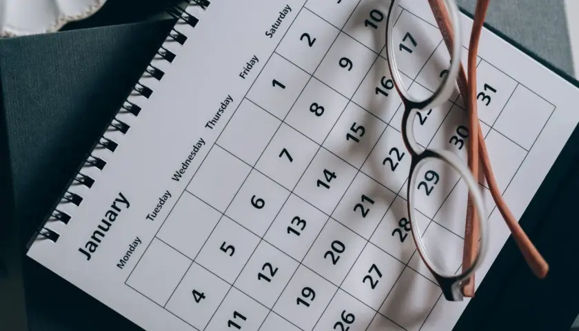 Okulary na kalendarzu pokazującym styczeń. Planowanie urlopu od kiedy 35 dni urlopu.