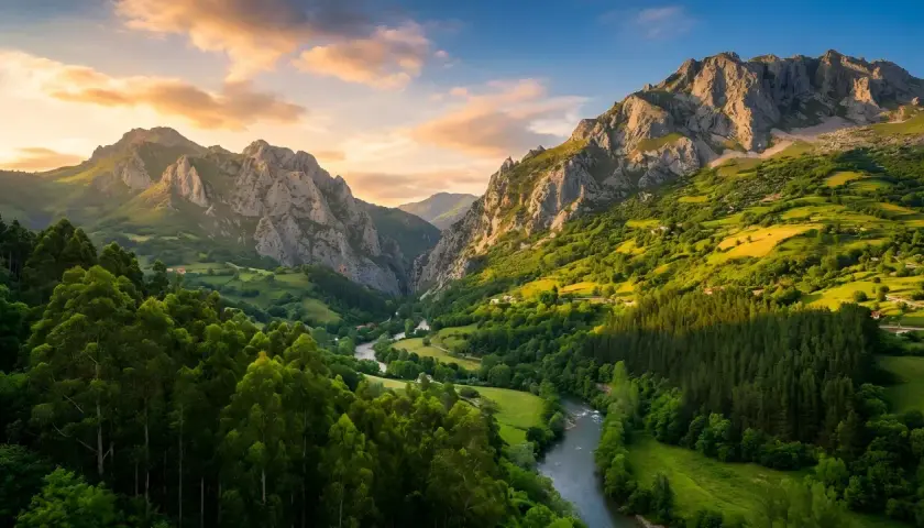 Un valle verde con un río serpenteante, montañas escarpadas y un cielo dorado. Parece la senda del oso, un lugar de belleza salvaje.