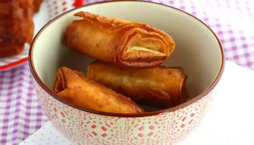 Krispiga, gyllene rullar med friterad banan panko i en mönstrad skål.