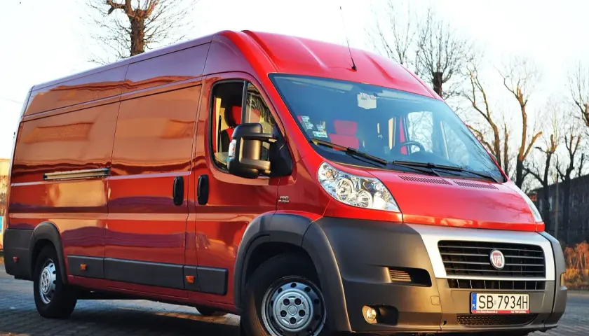 Czerwony Fiat Ducato Maxi zaparkowany na zewnątrz, gotowy do transportu.