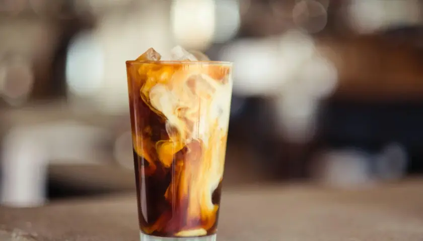 Ein Glas Eiskaffee mit Milchwirbeln und Eiswürfeln. Perfekt für ein iced coffee rezept schnell an heißen Tagen.