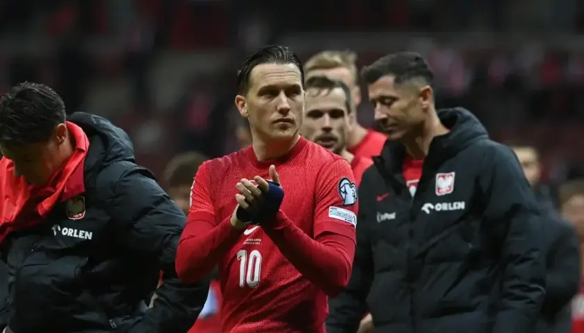 Piłkarze reprezentacji Polski, w tym Lewandowski, w czerwonych strojach i czarnych kurtkach, z nadzieją patrzą w przyszłość, marząc o baraze ms 2026.