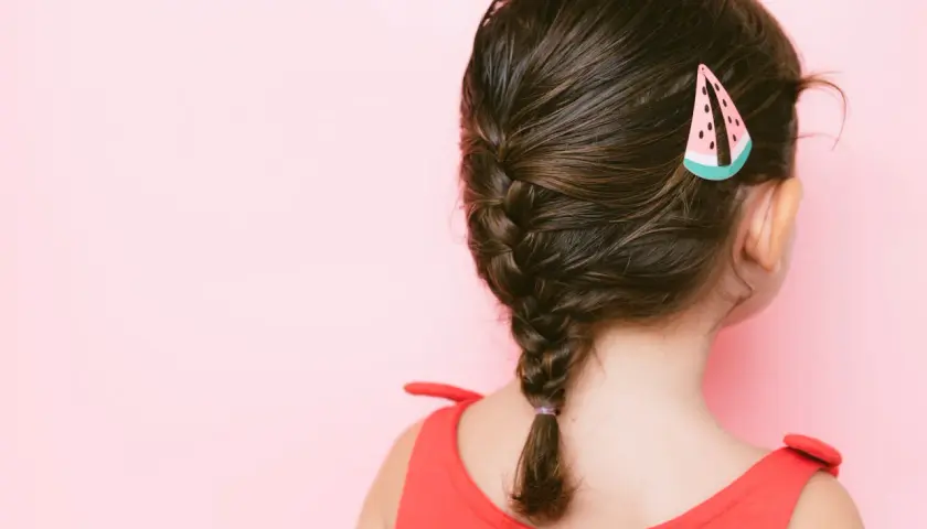 Niña con un bonito peinado de trenza y un pasador de sandía.