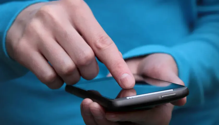 Palec dotyka ekranu smartfona, szukając rozwiązania, jak wyłączyć tryb awaryjny w telefonie.