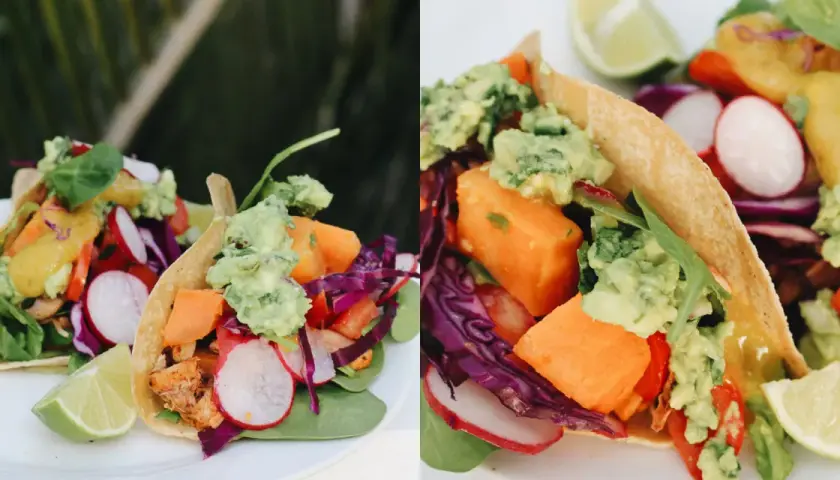 Deliciosos tacos vegetarianos con aguacate, camote, rábano y col morada, servidos con gajos de limón.