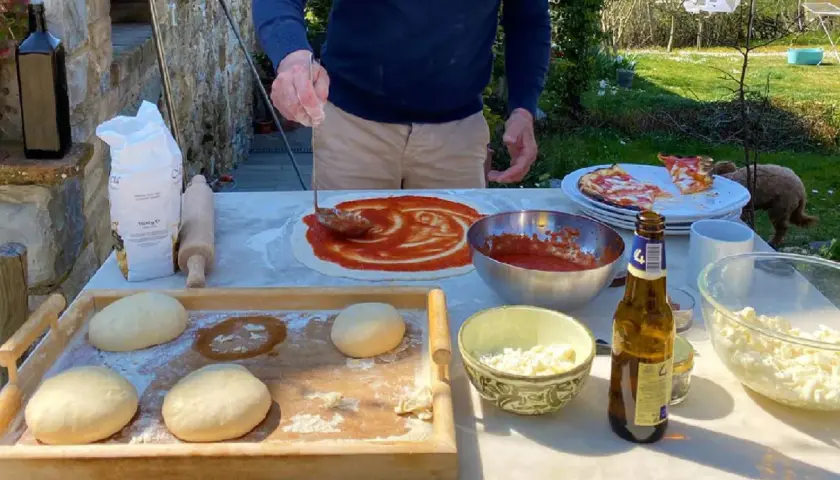 Przygotowanie pizzy w słonecznym Chianti, Włochy. Ciasto, sos pomidorowy i ser czekają na pieczenie.