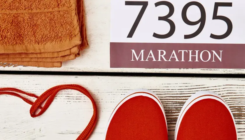 Pomarańczowy ręcznik, czerwone buty i numer startowy 7395 z napisem MARATON. Czas na maraton!