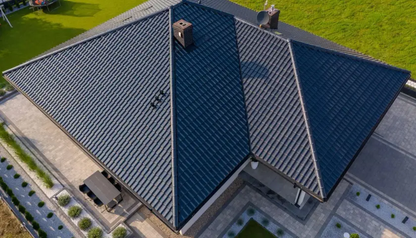 Nowoczesny dom z ciemnym dachem z dachówki ceramicznej. Różne rodzaje dachówek tworzą harmonijną całość.