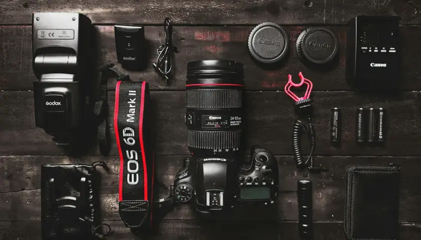 Zestaw sprzętu fotograficznego: aparat Canon EOS 6D Mark II, obiektyw Canon, lampa błyskowa Godox, akcesoria. Różne marki aparatów fotograficznych w jednym ujęciu.