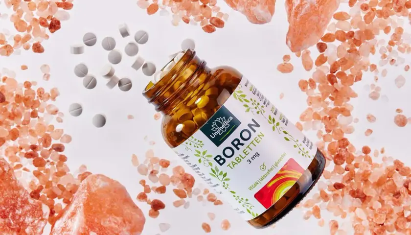 Braune Glasflasche mit BORON Tabletten, umgeben von rosa Salzkristallen und verstreuten Tabletten. Ein natürliches bor vitamin für Ihr Wohlbefinden.
