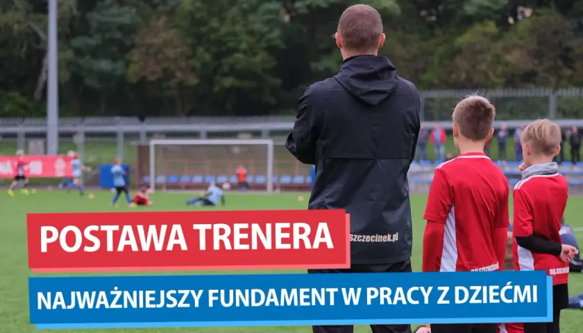Trener piłki nożnej obserwuje młodych zawodników na boisku. Jego postawa to fundament pracy z dziećmi.