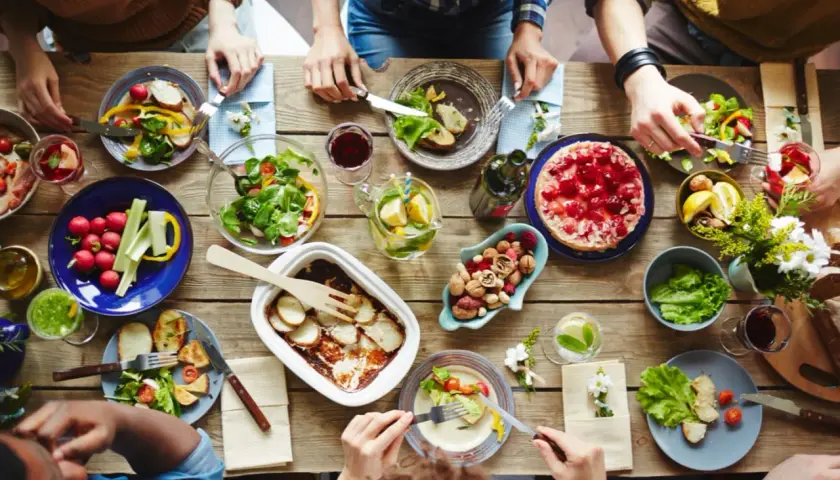 Leckeres Essen auf dem Tisch, aber was hilft gegen Appetit? Nüsse und frisches Gemüse sind eine gesunde Wahl.