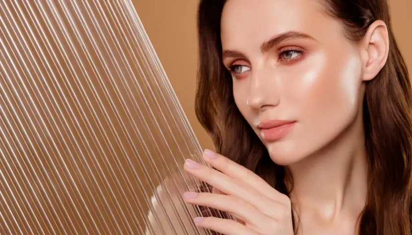 Kobieta z idealną cerą, która emanuje zdrowiem i blaskiem, osiągając efekt glass skin. Jej skóra jest gładka i świetlista, niczym tafla szkła.