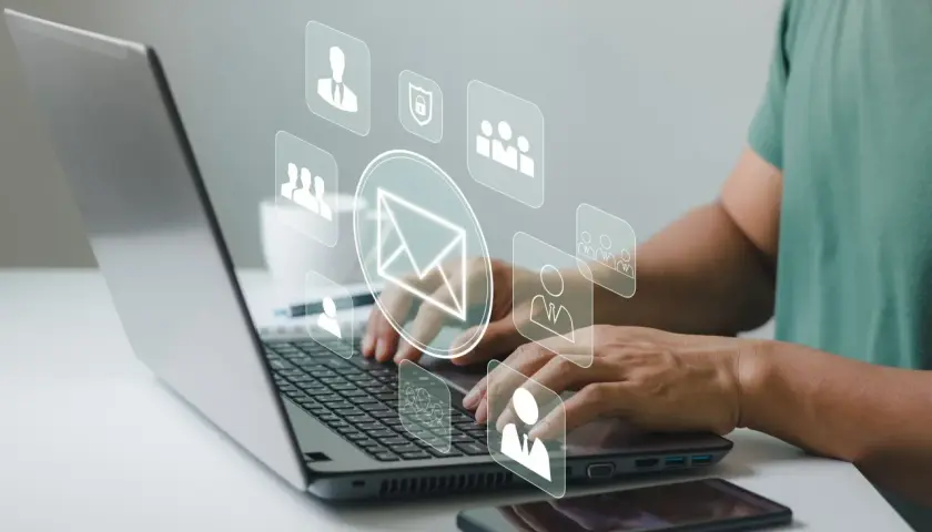Man typing on laptop, with icons representing communication and security, suggesting a secure correo electrónico certificado.