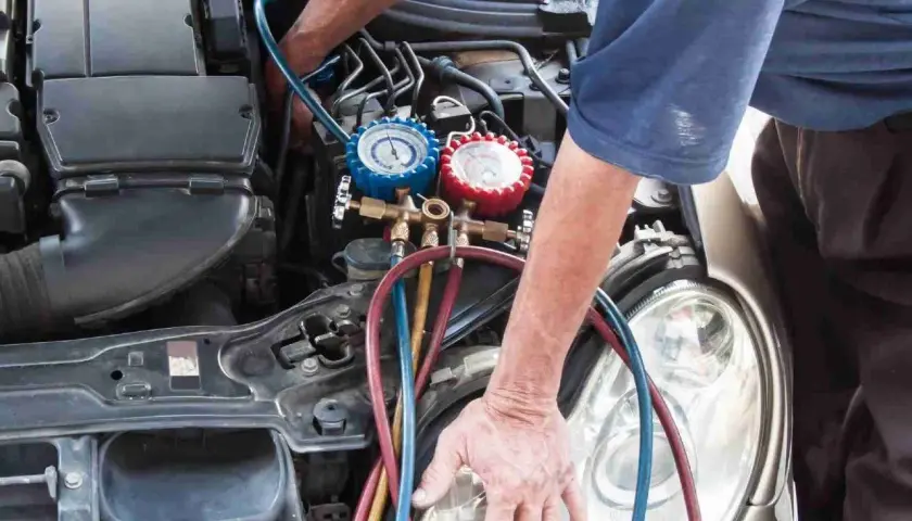 Mechanik sprawdza ciśnienie w układzie klimatyzacji. Objawy zapchanego osuszacza klimatyzacji mogą być trudne do zdiagnozowania.