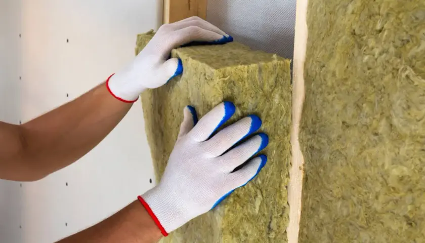 Mani guantate posizionano un pannello isolante per creare un solaio termico efficiente.
