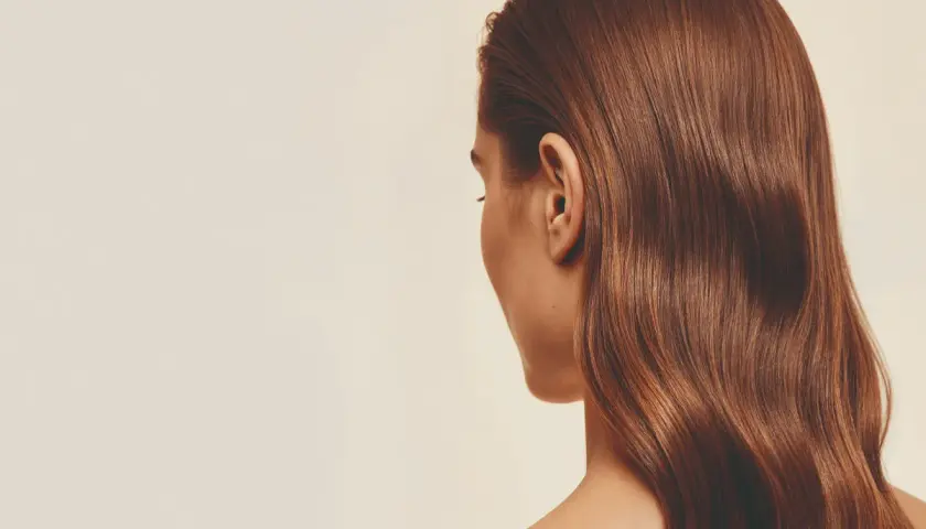 Cabello castaño brillante con un volumen envidiable, cayendo en ondas suaves sobre el hombro.