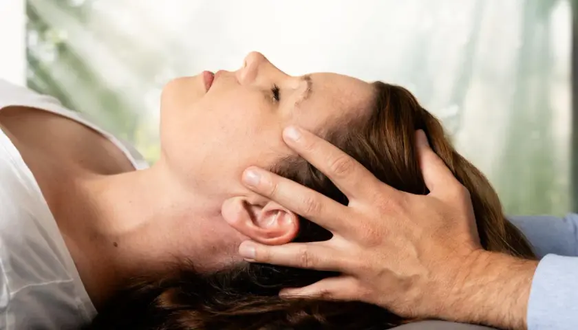 Osteopathie-Behandlung am Kopf, die den Nervus vagus stimuliert. Sanfte Berührung zur Entspannung.