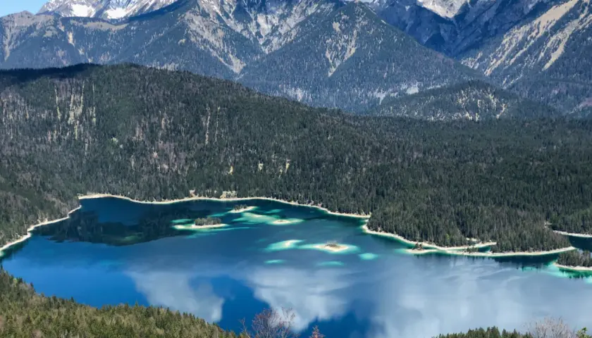Blick vom Eibsee zur Zugspitze: Türkisblaue Wasserflächen, bewaldete Hänge und schneebedeckte Gipfel. Ein Traumziel für Wanderer.