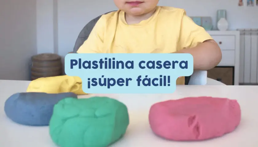 Un niño sonriente listo para jugar con plastilina casera para niños de colores: azul, verde, amarillo y rosa.