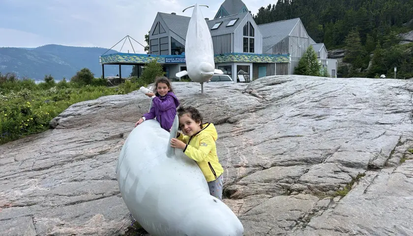 Due bambine giocano con sculture di balene a Canada orientale, vicino a un centro di interpretazione.
