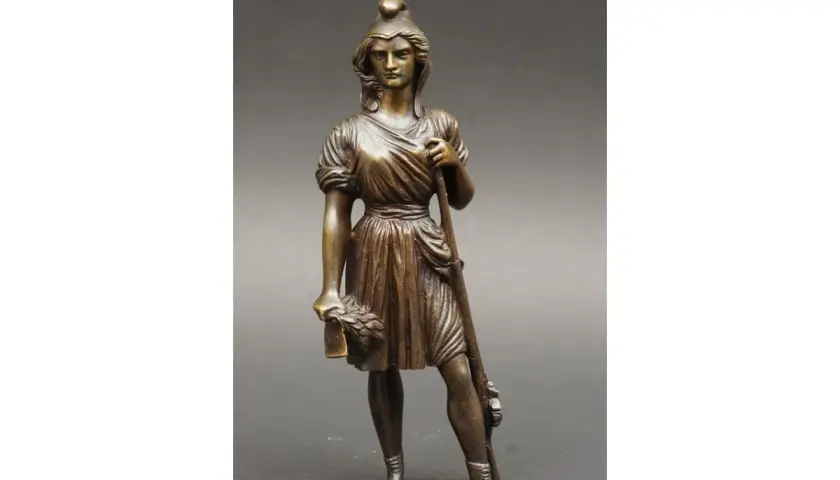 Brązowa figurka przedstawia Mariannę, kobietę symbol Republiki Francuskiej, z wieńcem laurowym i włócznią.