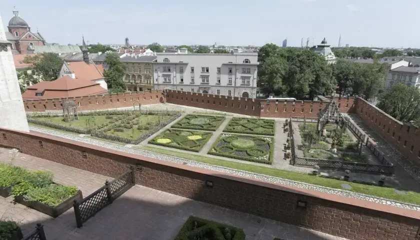 Krakowski ogród z geometrycznymi rabatami i architekturą, przypominający o dawnych czakramach w Polsce.
