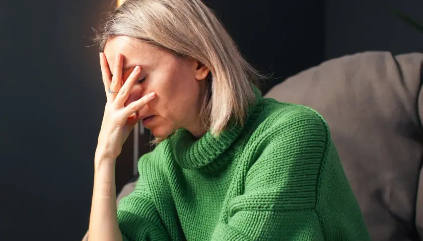 Donna con la mano sulla fronte, visibilmente provata. Un'immagine che evoca la lotta contro ansia e depressione, e la ricerca di come uscirne.