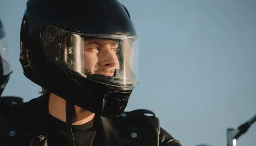 Hombre con casco de moto negro, listo para la aventura. Su mirada refleja la libertad y la seguridad que ofrece la homologación DOT.