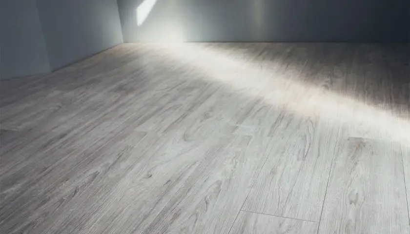 Pavimento in gres porcellanato effetto legno grigio, con luce che filtra dall'alto. Ideale per pulire fughe gres porcellanato effetto legno.
