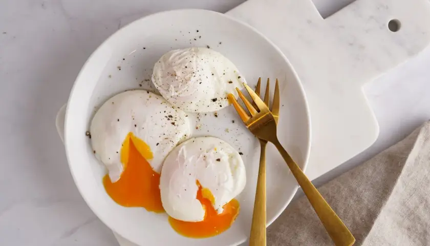 Trois œufs pochés parfaits, avec leurs jaunes coulants, assaisonnés de poivre noir. Un délice de différents types d'œufs pour un petit-déjeuner gourmand.