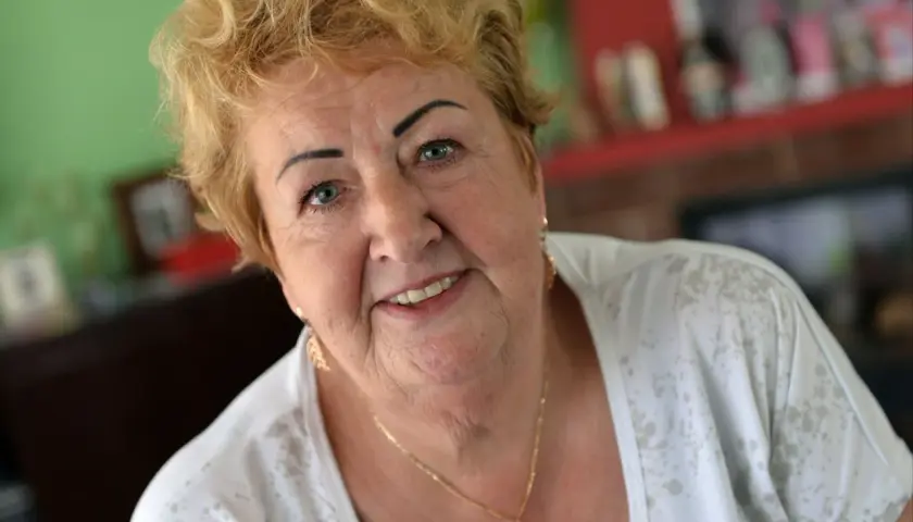 Uśmiechnięta Henryka Krzywoń Strycharska z blond włosami i złotym naszyjnikiem.