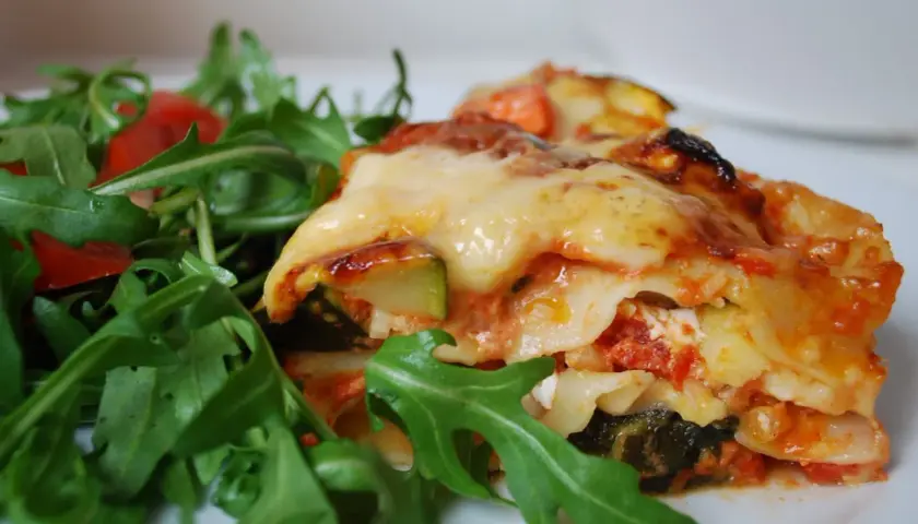 En bit krämig grönsakslasagne med ruccolasallad, perfekt för en vegetarisk recept topplista.