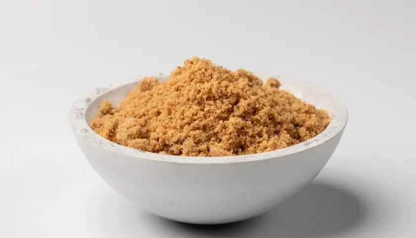 Schüssel mit dunklem Muscovado-Zucker, dessen feine Körner eine warme, karamellige Farbe haben.
