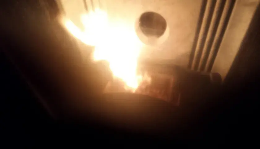 Flammes vives dans un poêle Piazzetta, peut-être un problème de tirage. La chaleur intense illumine l'intérieur.