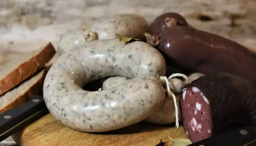 Kaszanka i biała kiełbasa na desce, obok chleb i noże. Zastanawiasz się, czy można zamrozić kaszankę? Tak, można!