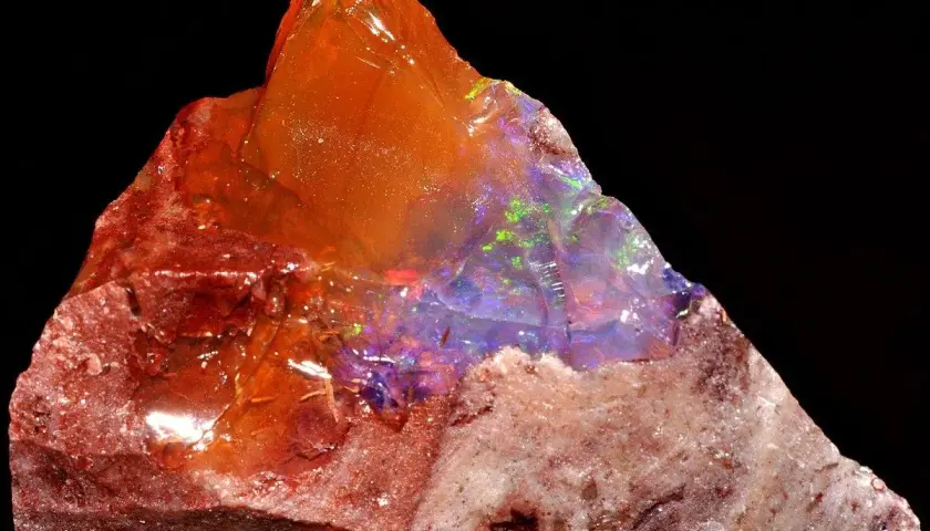 Ein roher Feueropal mit leuchtenden Farben, dessen feurige Wirkung durch das Spiel von Licht und Farbe im Stein fasziniert.