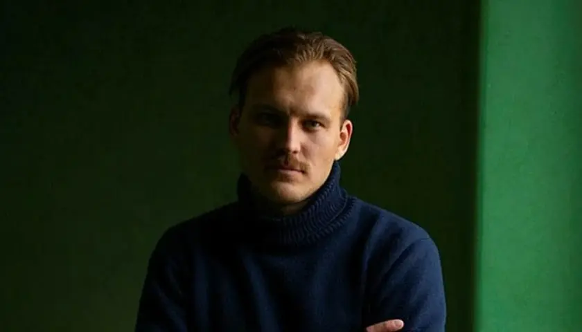 Pascal Engman, med mustasch och mörk polotröja, poserar framför en mörkgrön bakgrund.